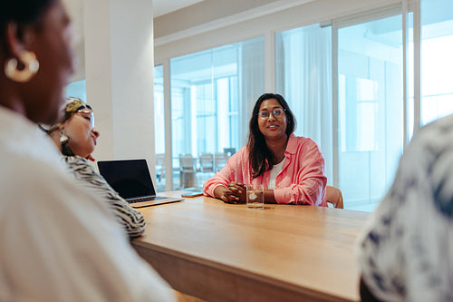 Female business owner leading a meeting with diverse colleagues discussing new strategies