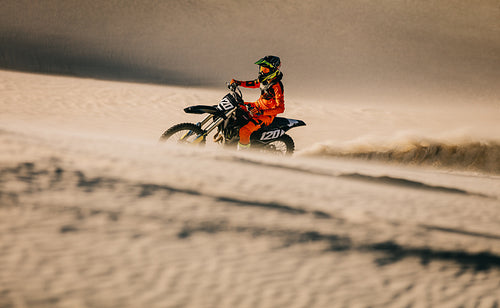 Professional motocross biker racing in sand dunes