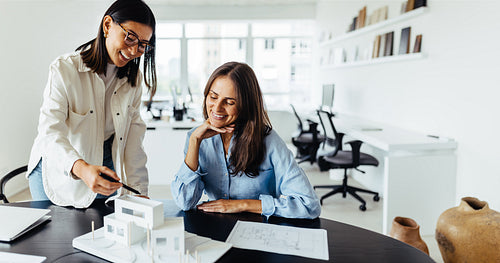 Two female architects discussing a 3D model in an office