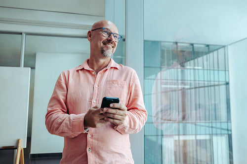 Mature professional entrepreneur smiling confidently while using a smartphone