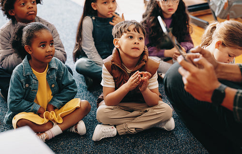 Listening comprehension lesson in an elementary class. Kids pay attention to their teacher reading a story