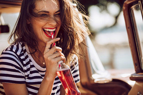 Woman in car enjoying drinking cola