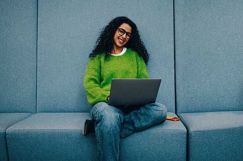 Young woman working on laptop in library lounge