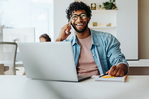 Happy entrepreneur working on laptop in modern office