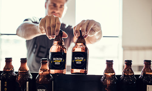 Young man inspecting the beer bottles on conveyor belt
