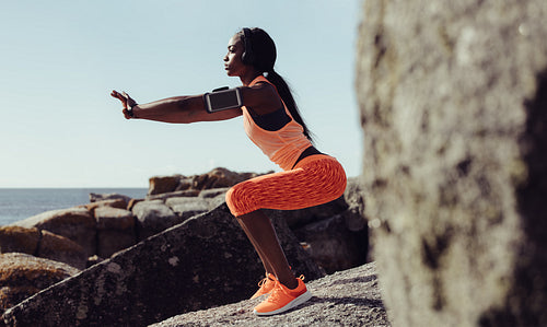 Healthy woman stretching at seaside rocks