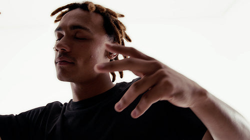 Young man with dreadlocks dancing happily to music through his earbuds