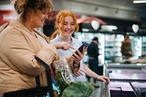 Shopper asking supermarket worker for help finding a food item