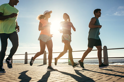 Group of runners running on road by the seaside