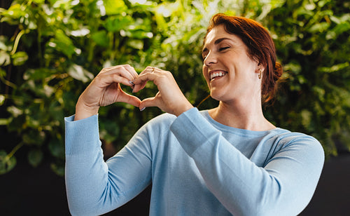 Showing love for sustainability: Business woman displays a heart gesture in a green office