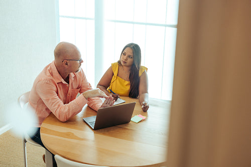 Colleagues engaged in a productive business meeting at a desk with a laptop