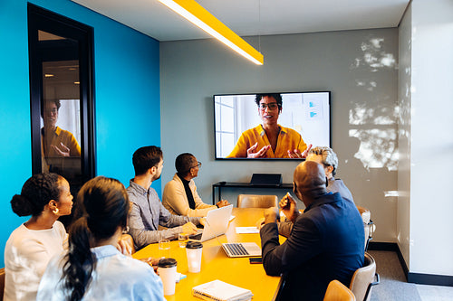 Group meeting with virtual speaker on screen in professional conference room