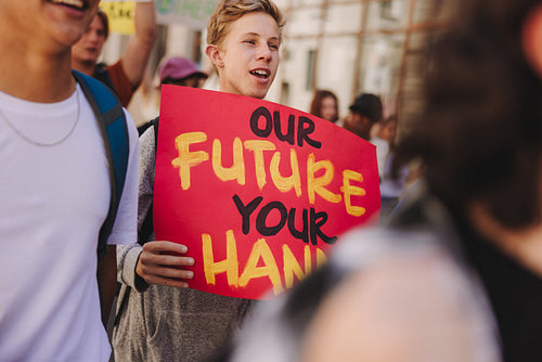 Teenage boy holding a banner during a climate change protest