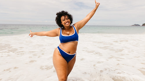 Celebrating at the beach: Plus size woman dancing and enjoying herself in a bikini