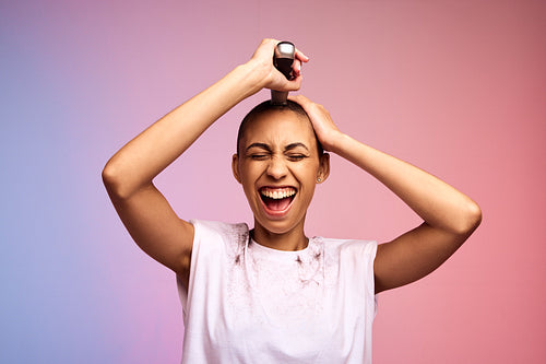 Happy woman trimming her head to bald