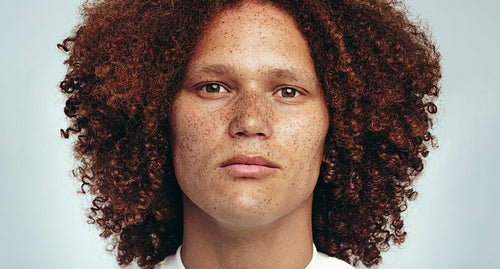 Portrait of a handsome man with freckles and an afro looking at the camera