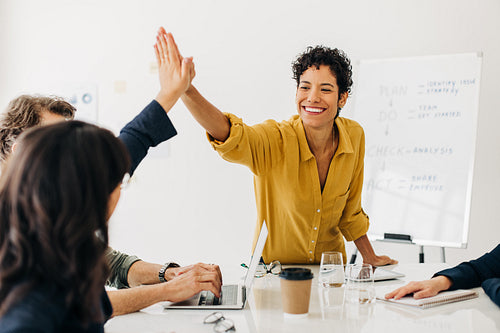Successful women doing a high five in a meeting