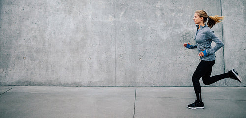 Young woman running on sidewalk in morning