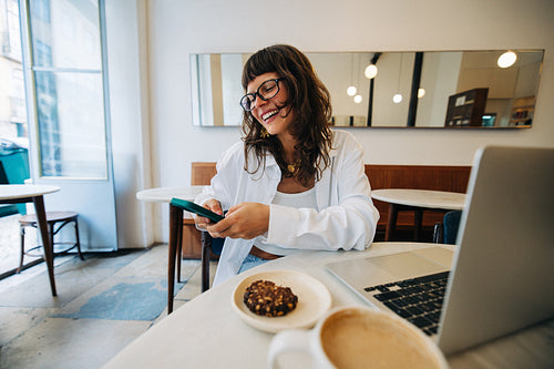 Smiling woman working on laptop in a cafe