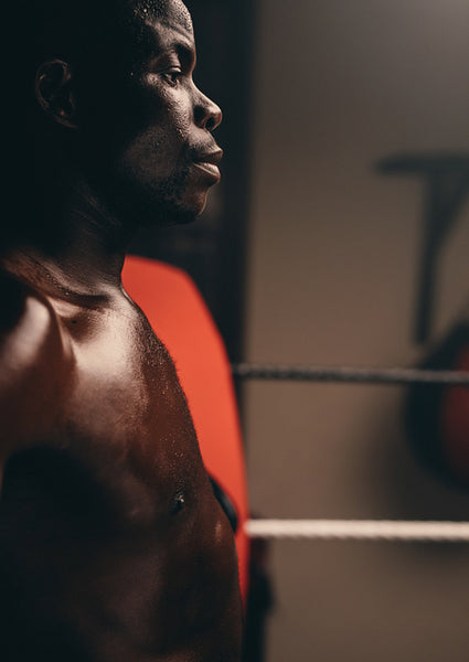 Shirtless young boxer standing in a boxing ring