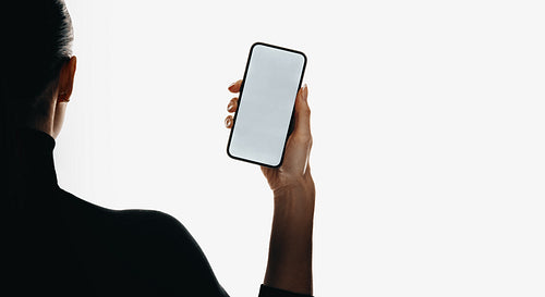 Person holding a smartphone with a white screen against a minimal background