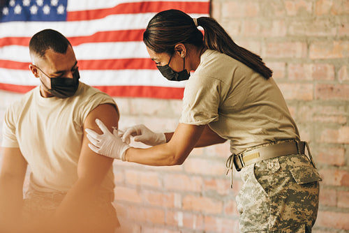 Female doctor administering the covid-19 vaccine to a soldier