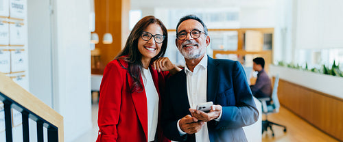 Senior executives smiling confidently during informal meeting in a bright office environment