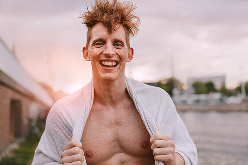 Handsome young man wrapped in towel and smiling