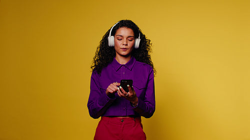 Young woman enjoys music on her phone and dances with headphones