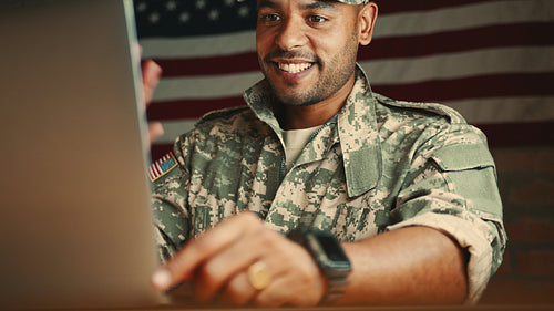Deployed and connected: Soldier in camouflage clothing sits in front of a laptop video calling his family