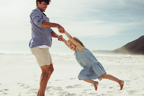 Father playing with his daughter on beach vacation.