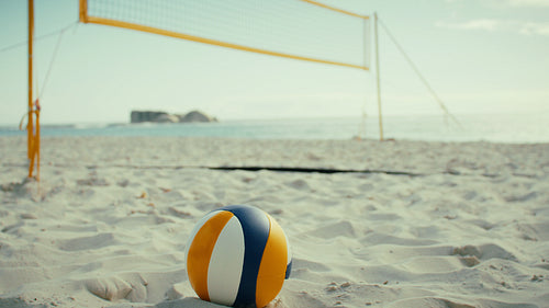 Static shot of empty beach volleyball field with a ball in the foreground