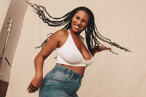 Cheerful young woman celebrating being natural in a studio