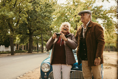 Senior couple taking picture on car trip