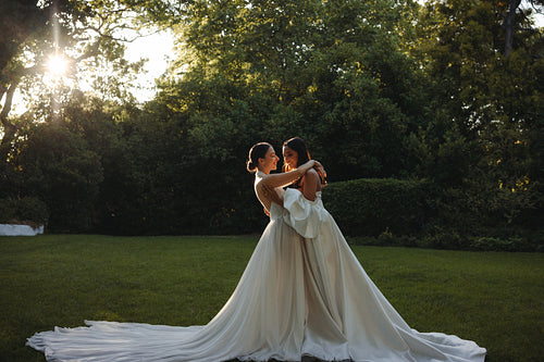 Romantic portrait of two brides embracing during an outdoor wedding ceremony