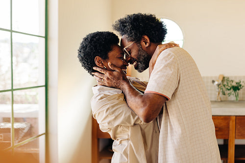 Happy afro-brazilian couple sharing intimate moment in kitchen