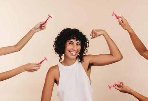 Empowered woman flexing her unshaven underarm