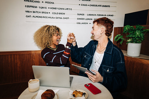 Friends celebrate collaboration and success in a cafe