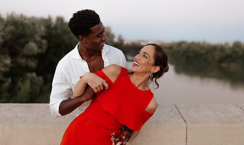 Modern couple laughing happily on a bridge