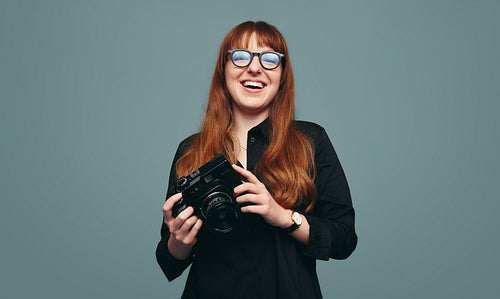 Cheerful female photographer smiling at the camera in a studio