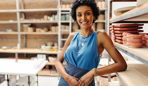 Young potter smiling at the camera in her shop