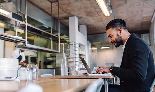 Business man sitting at restaurant working on laptop
