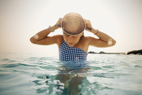 Young girl putting on a swimming mask during a family vacation