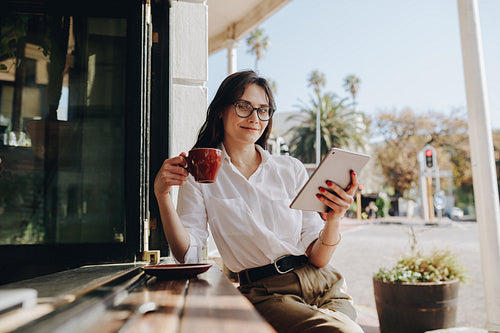 Businesswoman at cafe with cup of coffee and digital tablet