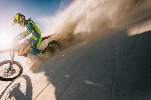 Professional motocross biker riding on sand dunes