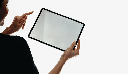 Woman interacting with blank tablet screen in an isolated environment