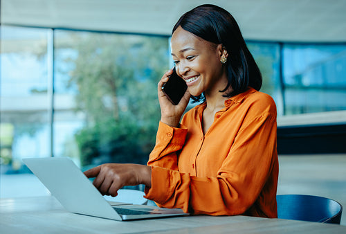 Businesswoman multitasking on a phone call while using a laptop