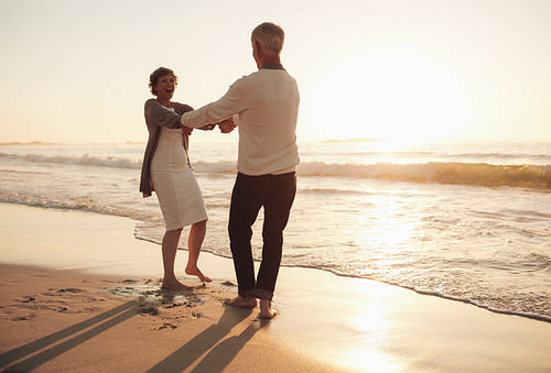 Smiling senior couple having fun on the beach