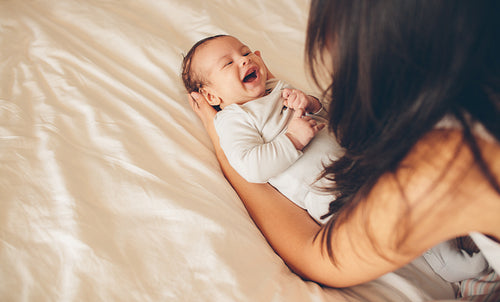 Mother playing with her baby boy on bed
