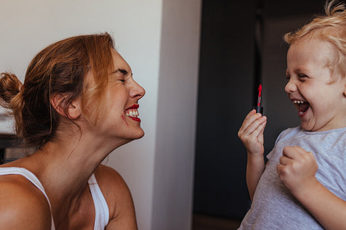Cute little boy applying makeup to his mother